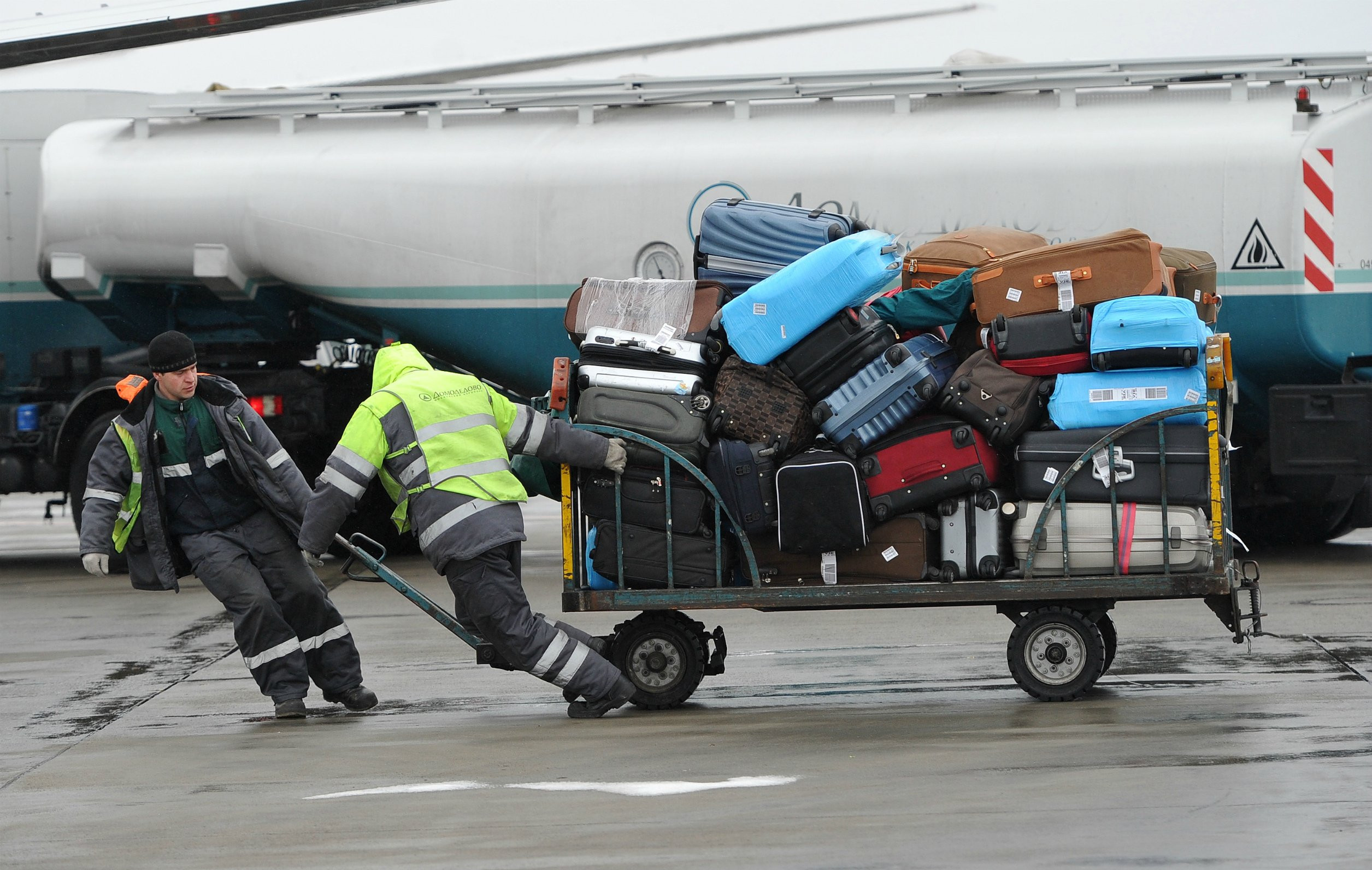 Воздушных перевозок пассажиров грузов. Погрузка багажа в самолет. Погрузка чемоданов в самолет. Погрузка багажа в аэропорту. Тележка для багажа в аэропорту.