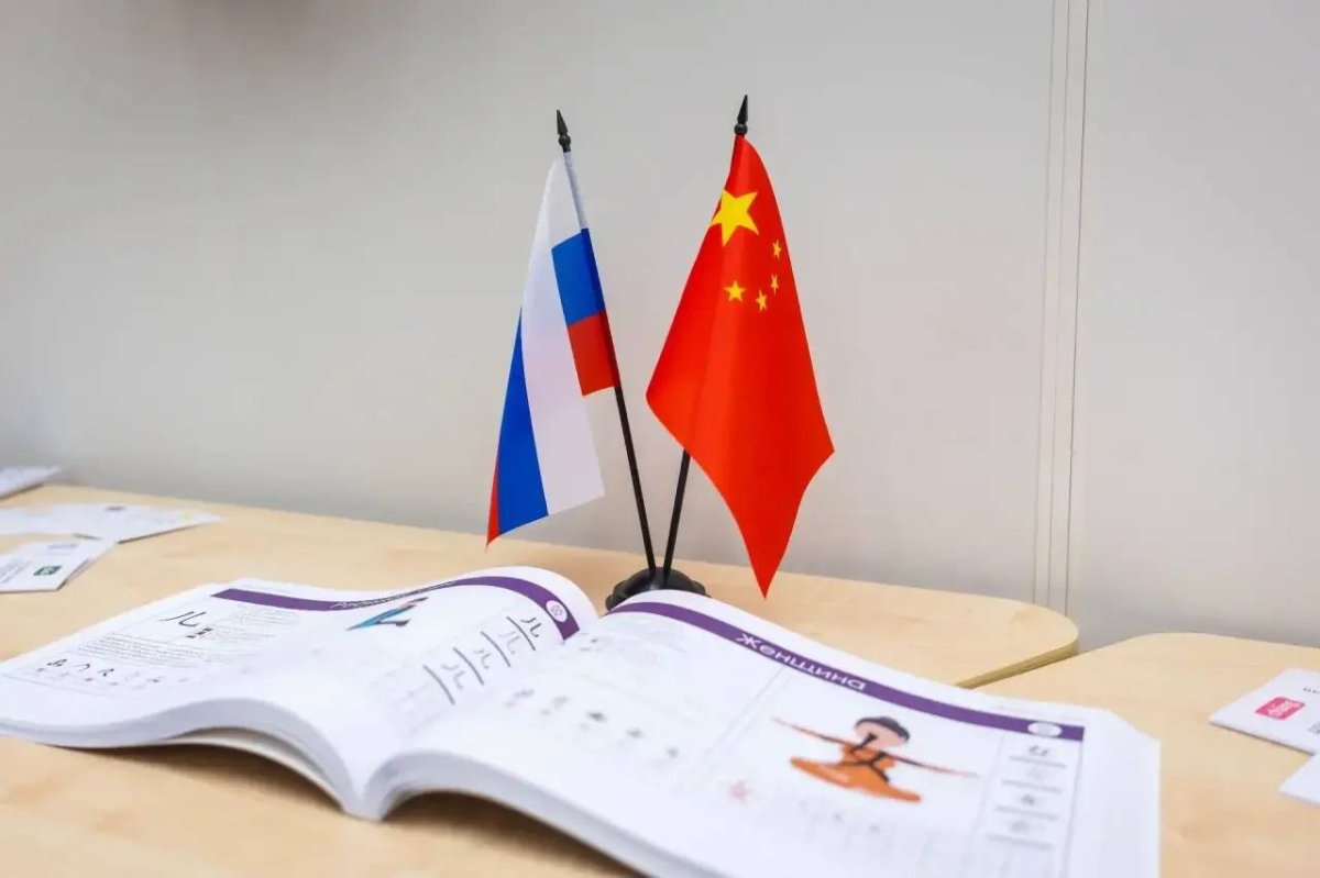 Раскрытый буклет и два маленьких государственных флага России и КНР.