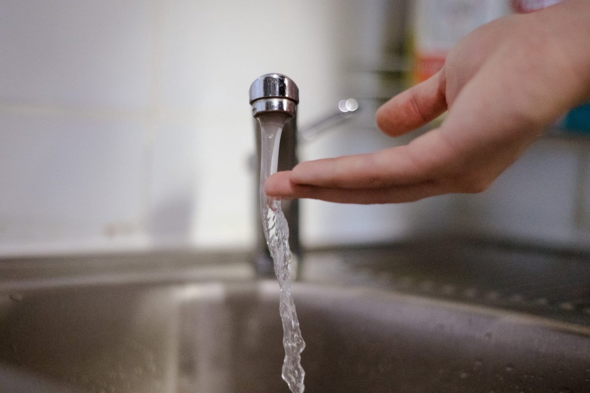 Из крана бежит вода. Под струей воды рука.