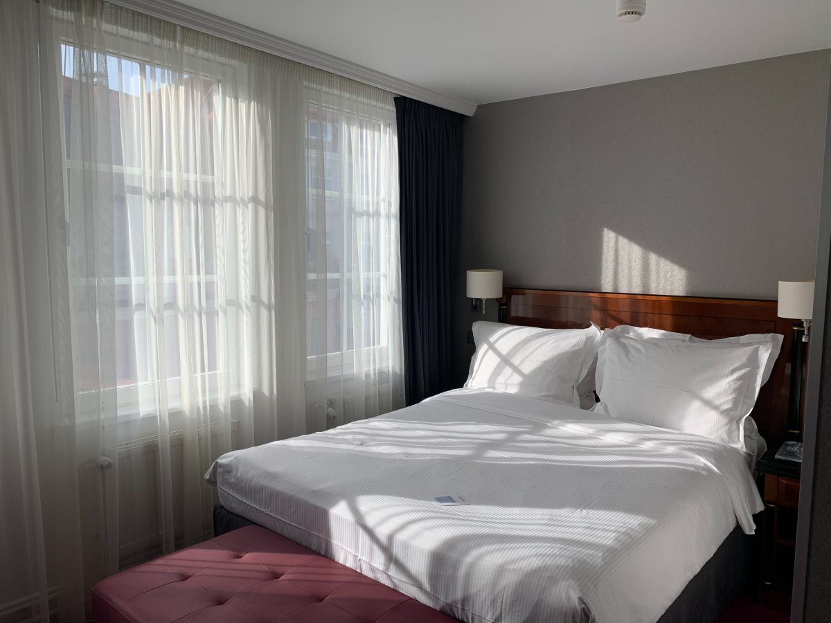 Кровать в отеле на фоне окна