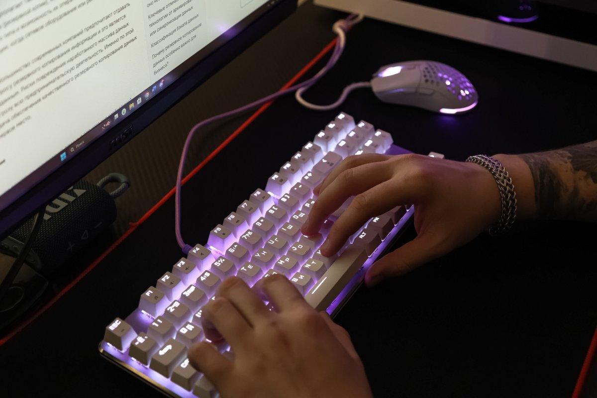 Руки человека, работающего на клавиатуре компьютера.