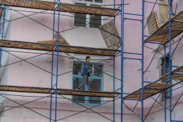 Работник ходит по строительным лесам.