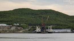 Левый, западный берег Кольского залива в Мурманской области с двумя стоящими на причале судами.