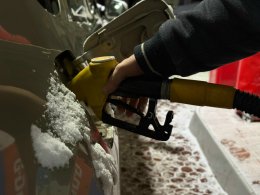 Мужчина держит заправочный пистолет в баке