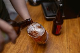 Мужчина наливает пиво в стакан.