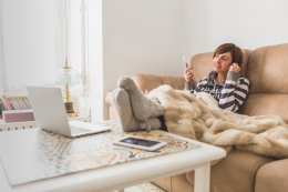 Девушка отдыхает дома, сидя на диване и вытянув ноги в теплых носках.