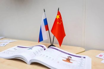 Раскрытый буклет и два маленьких государственных флага России и КНР.
