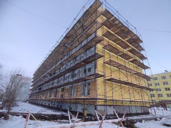 Жилой дом в строительных лесах в Мурманской области зимой.