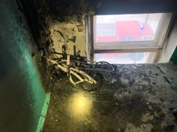 Сгоревшая детская коляска на лестничной площадке.