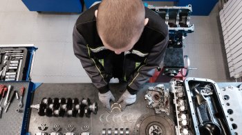 Автослесарь рассматривает детали.