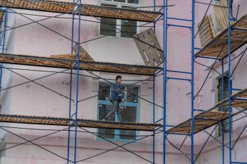 Работник ходит по строительным лесам.