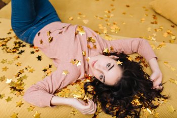 Девушка лежит и смотрит в камеру, усыпанная блестящими звездами