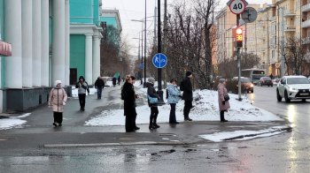 Люди стоят у пешеходного перехода.