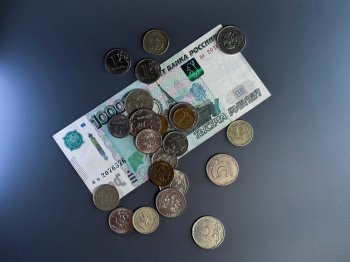Монеты и купюра номиналом 1000 рублей лежат на столе.