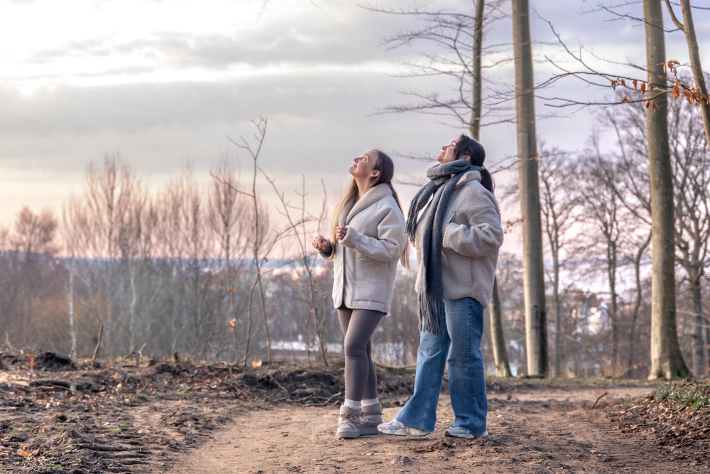 Две девушки весной смотрят на небо во время прогулки