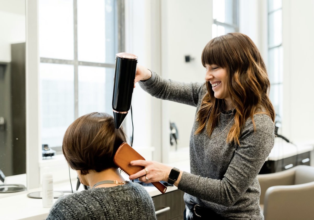 Стилист сушит голову клиенту феном