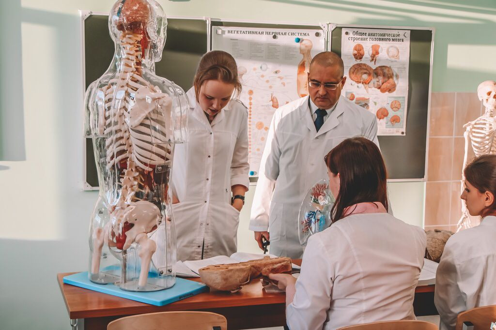 Студенты и преподаватель в белых халатах.