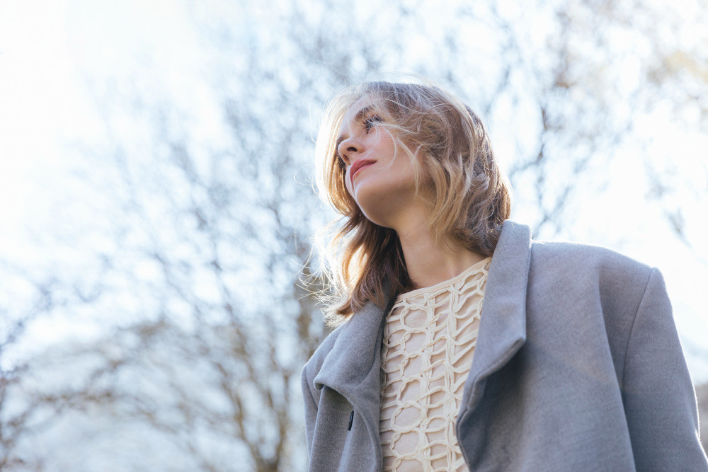 Девушка в сером пальто на фоне неба