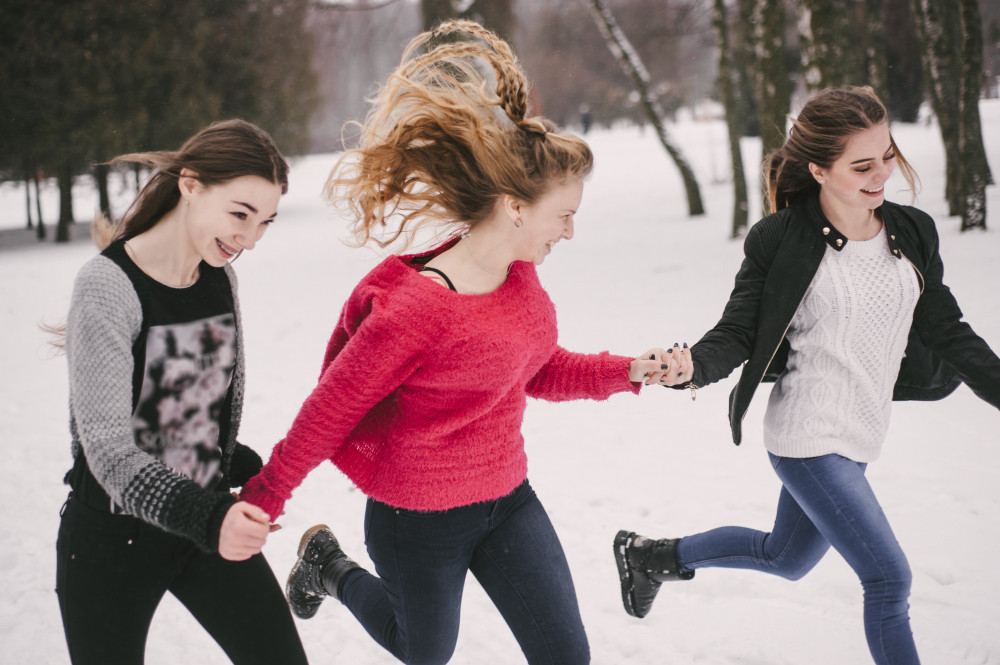3 девушки бегут по улице, взявшись за руки.