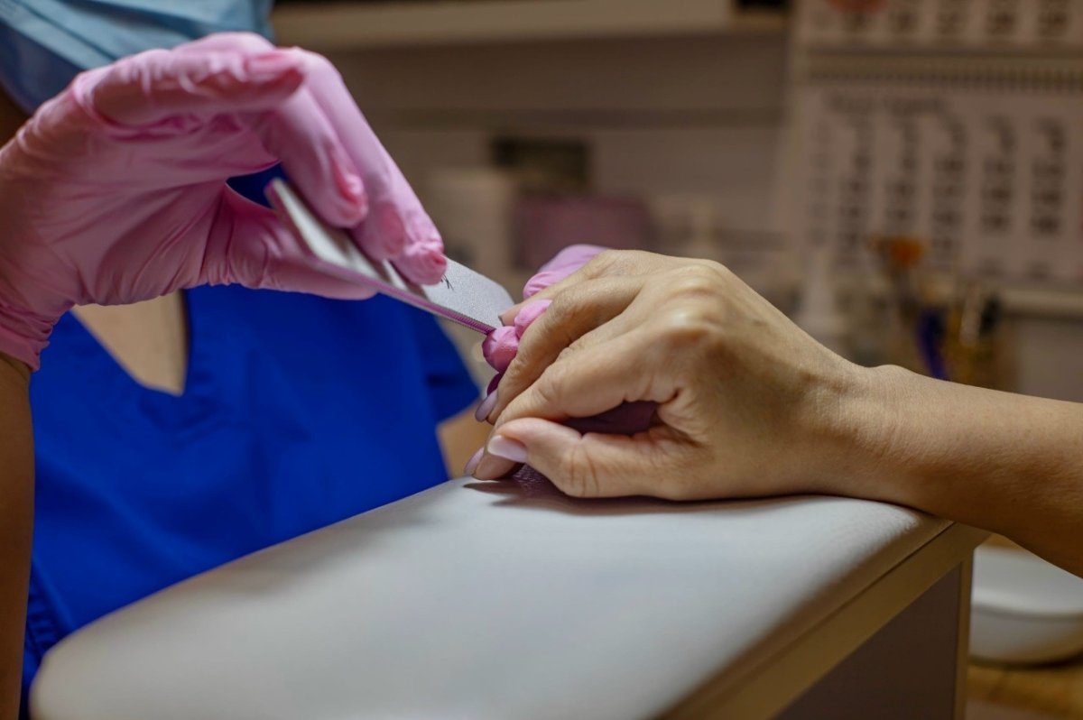 Женщине делают маникюр.