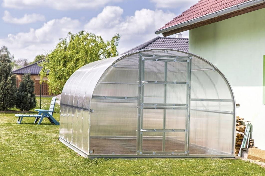 теплица из поликарбоната на зеленом газоне