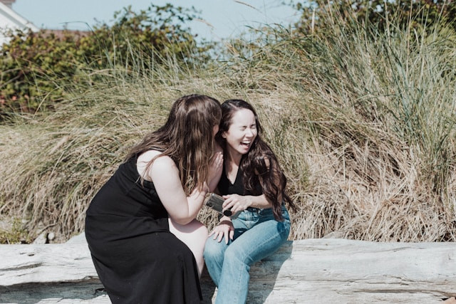 девушка на пляже шепчет подруге на ухо