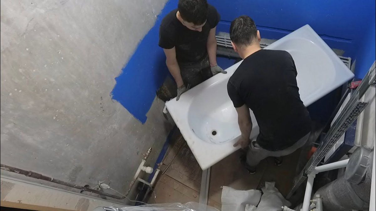 двое рабочих заносят ванну в санузел