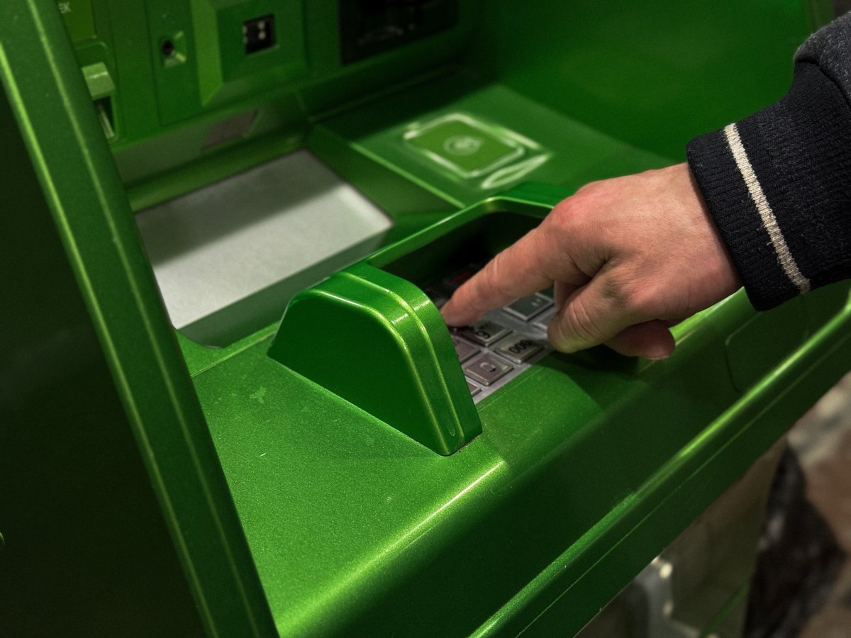 Мужчина снимает наличные в банкомате.