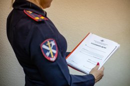 Женщина в полицейской форме держит папк в уголовным делом.