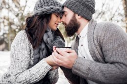 Мужчина и женщина обнимаются на улице, держа одну чашку