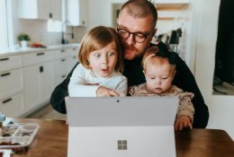 Отец с детьми смотрит в ноутбук.