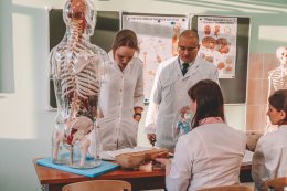 Студенты и преподаватель в белых халатах.