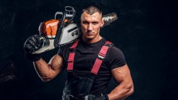мускулистый мужчина с бензопилой на плече