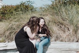 девушка на пляже шепчет подруге на ухо