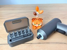 Шуруповёрт и конструктор стоят на столе.