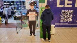 Мужчина снимает деньги в банкомате рядом с предупреждением о мошенниках