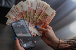 Деньги и телефон с изображением виртуального мошенника