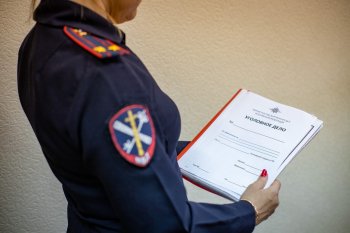 Женщина в полицейской форме держит папк в уголовным делом.