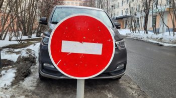 Дорожный знак, запрещающий парковку, и стоящий за ним автомобиль в Мурманске