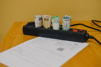 Квитанция и свернутые трубочкой денежные купюры  в колодке в розетками