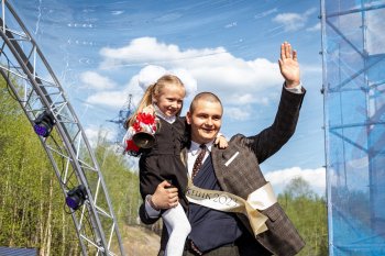 Выпускник с девочкой в школьной форме на руках. девочка держит колокольчик.
