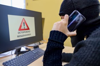 Мошенник разговаривает по телефону.