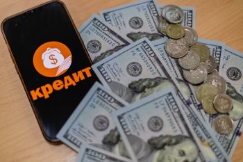 Телефон рядом с деньгами, взятыми в кредит.