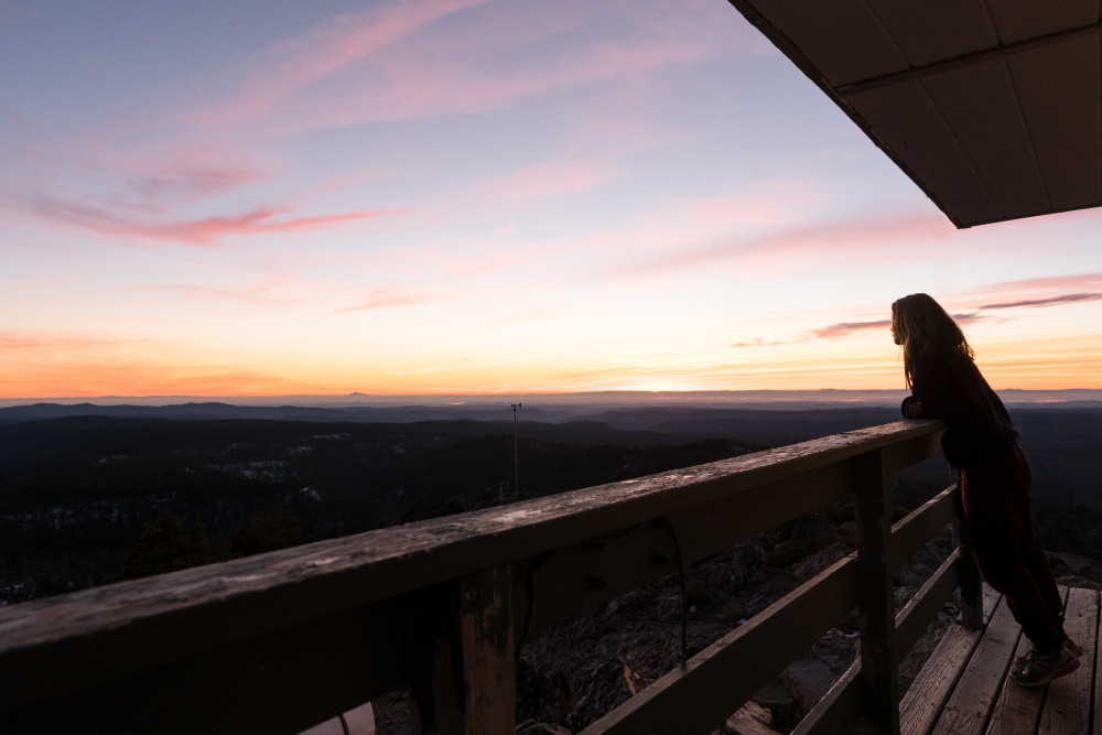 Девушка смотрит с балкона на вечернее небо.