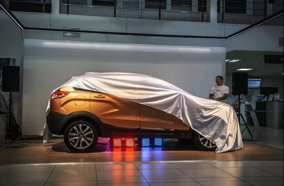 новый автомобиль под покрывалом на выставке