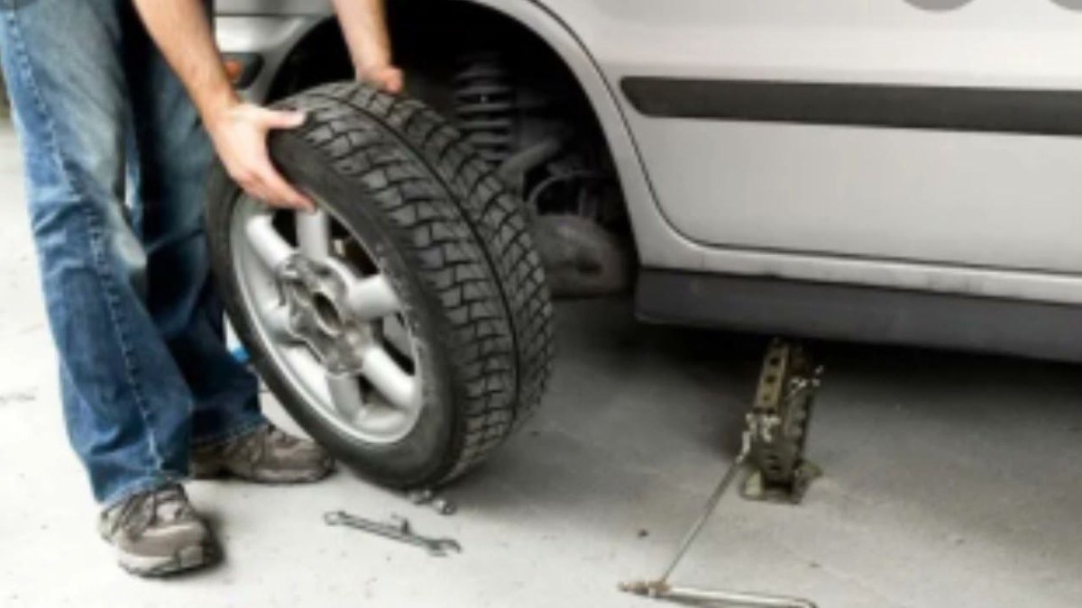 механик ставит колесо на ось