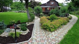 сад с клумбами и дорожкой из плитки