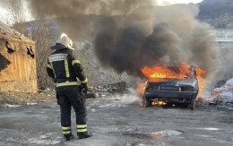 Пожарный смотрит на горящий автомобиль