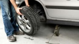 механик ставит колесо на ось