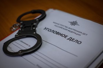 Наручники лежат на папке с уголовным делом.